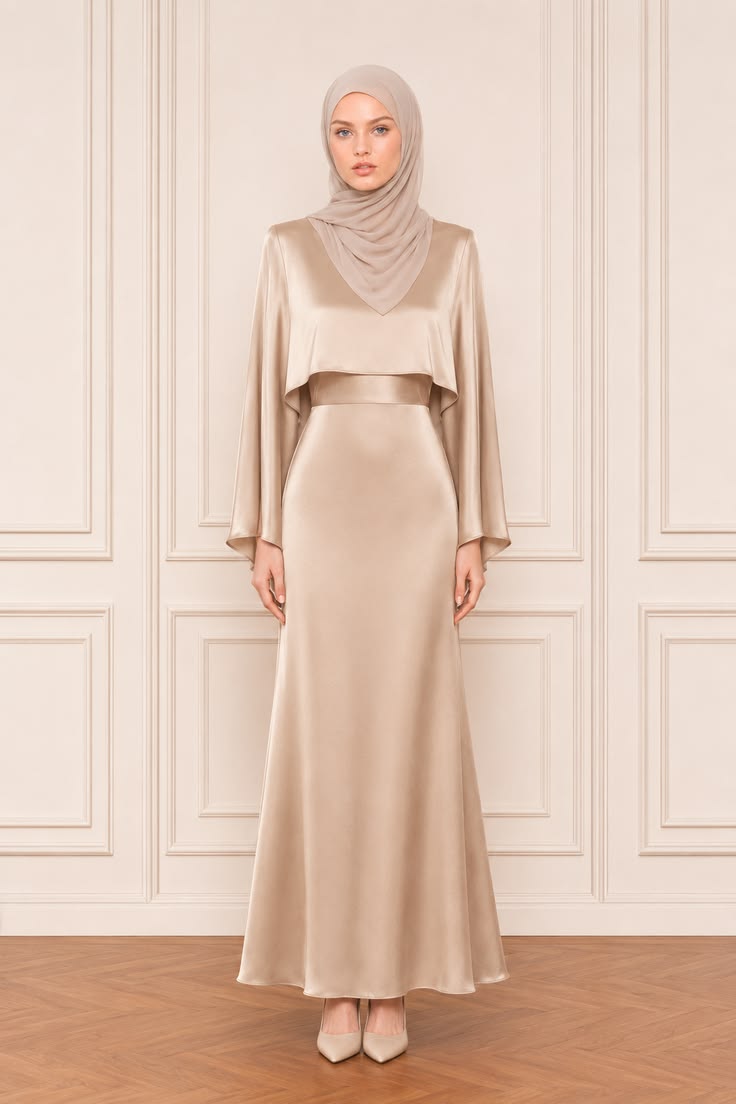 Minimalist modest formal gown with a champagne satin cape overlay, long column skirt, matching waist band, taupe hijab, and pointed heels.