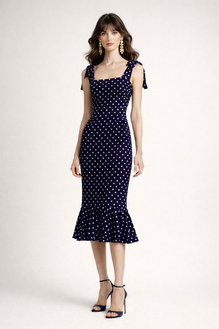 Parisian summer outfit with a fitted navy and white polka-dot midi dress, shoulder ties, ruffled hem, gold earrings, and navy sandals.